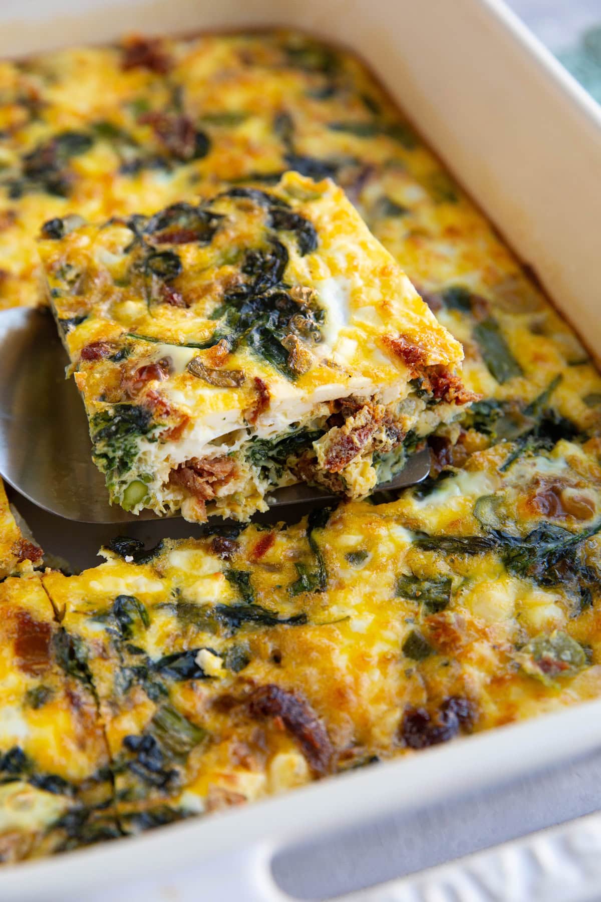Breakfast Casserole in a casserole dish with a slice taken out so you can see the inside.