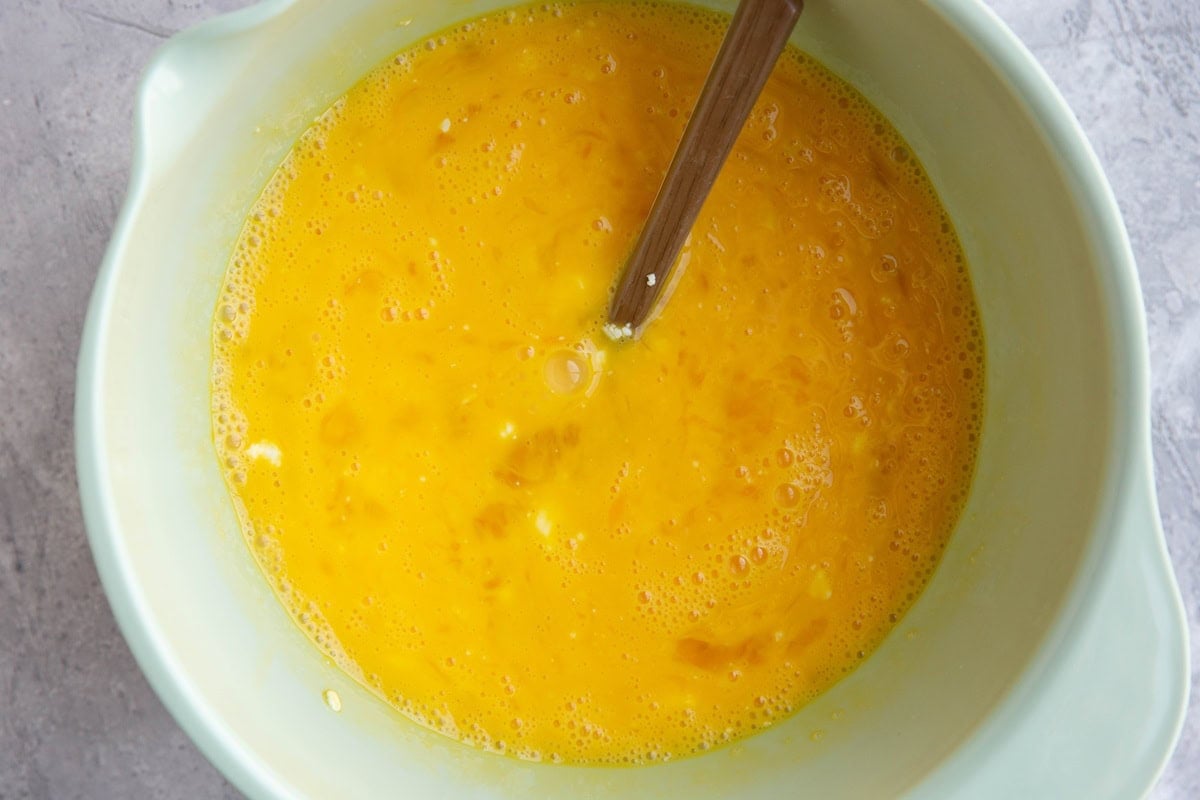 Mixing bowl full of beaten egg with feta cheese.