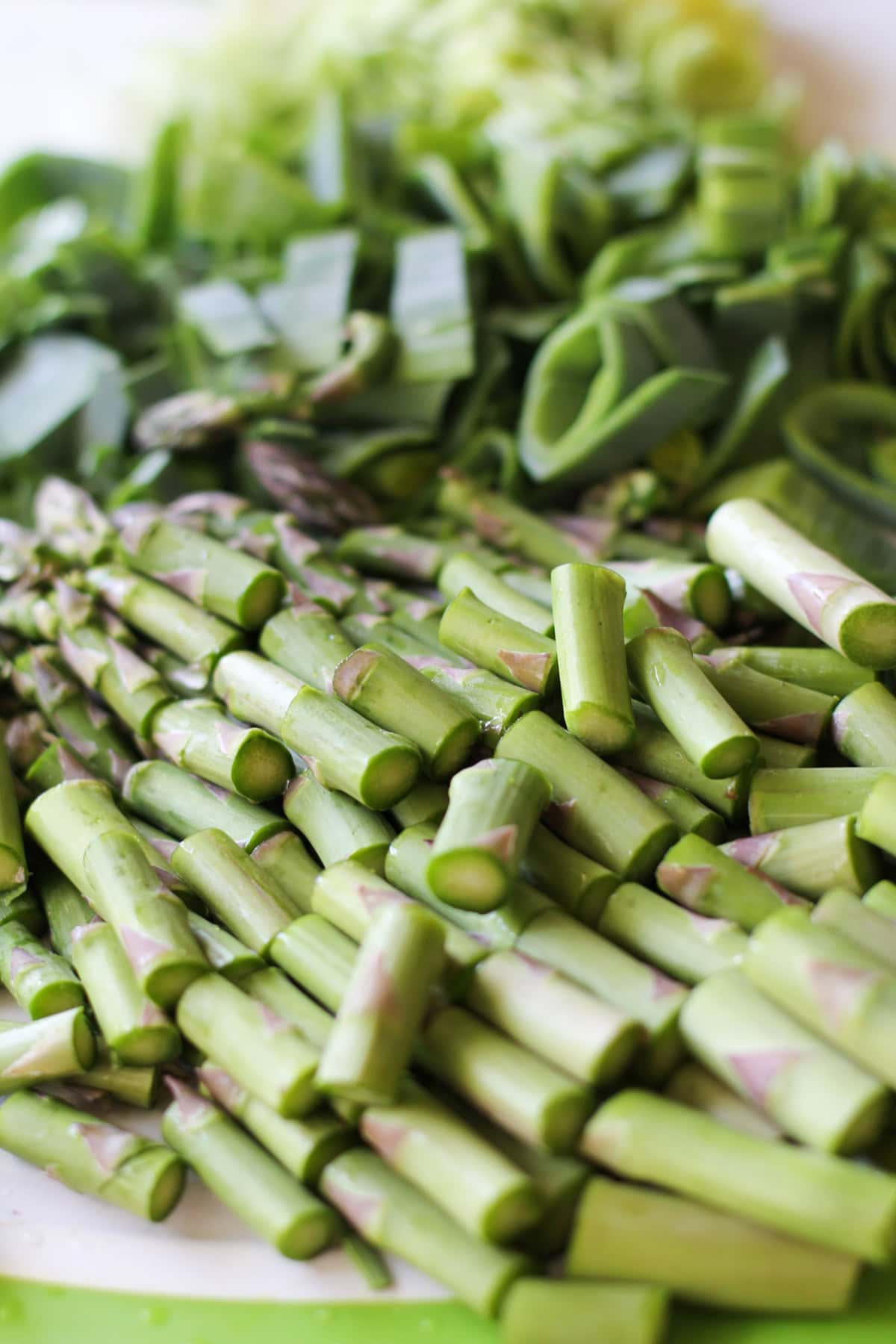 Cutting board with chopped asparagus and chopped leek.