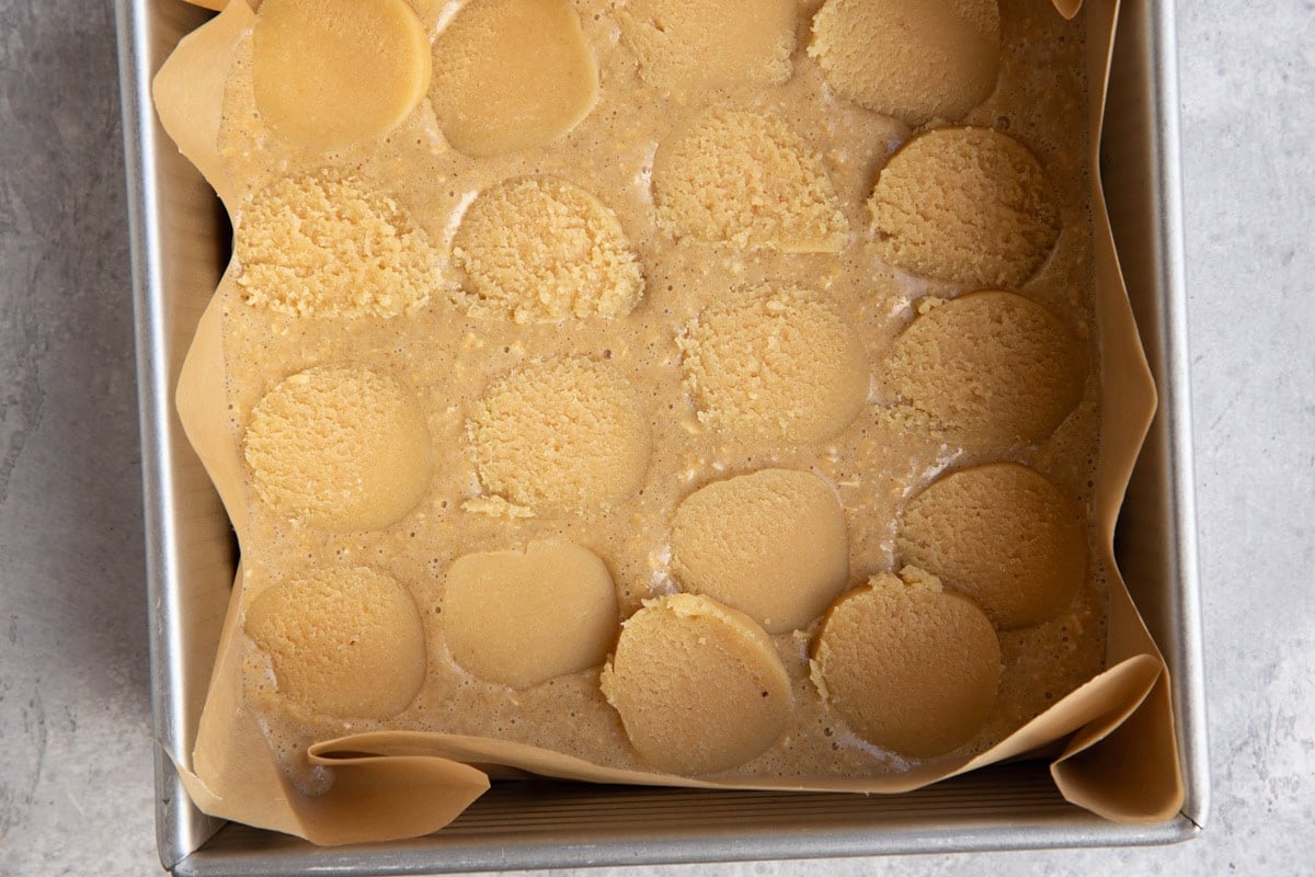 Cake pan with cake batter and a layer of almond paste slices.