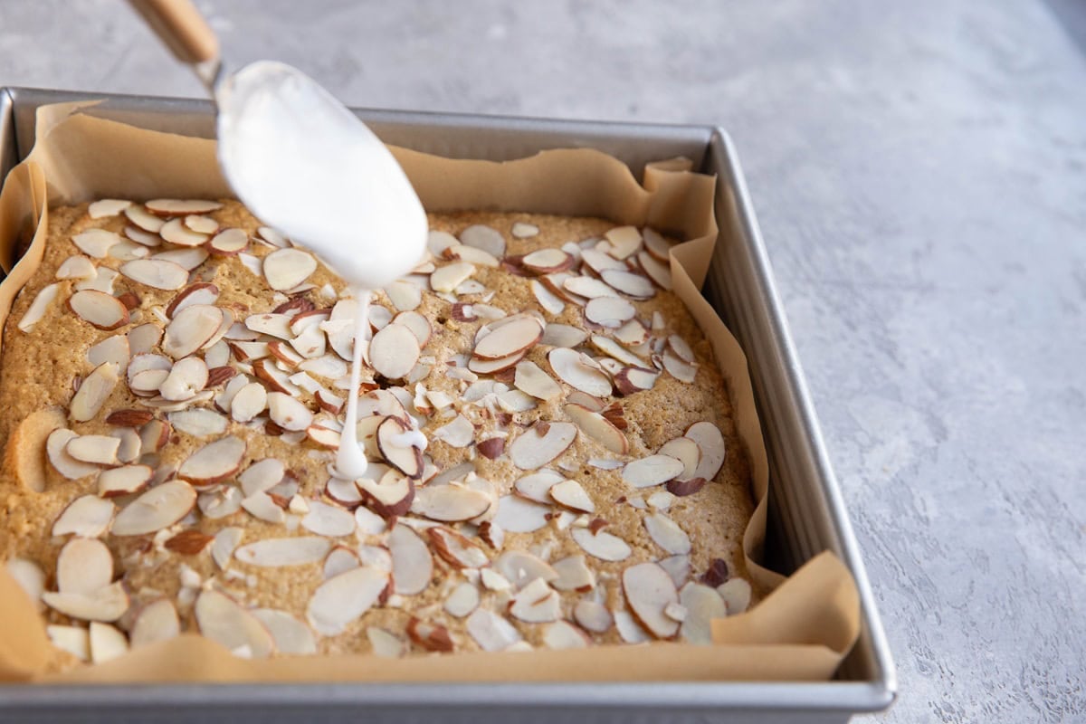 Drizzling glaze over cooked bear claw cake.