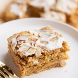 Slice of bear claw cake with a gold fork on a white plate with the rest of the cake in the background.