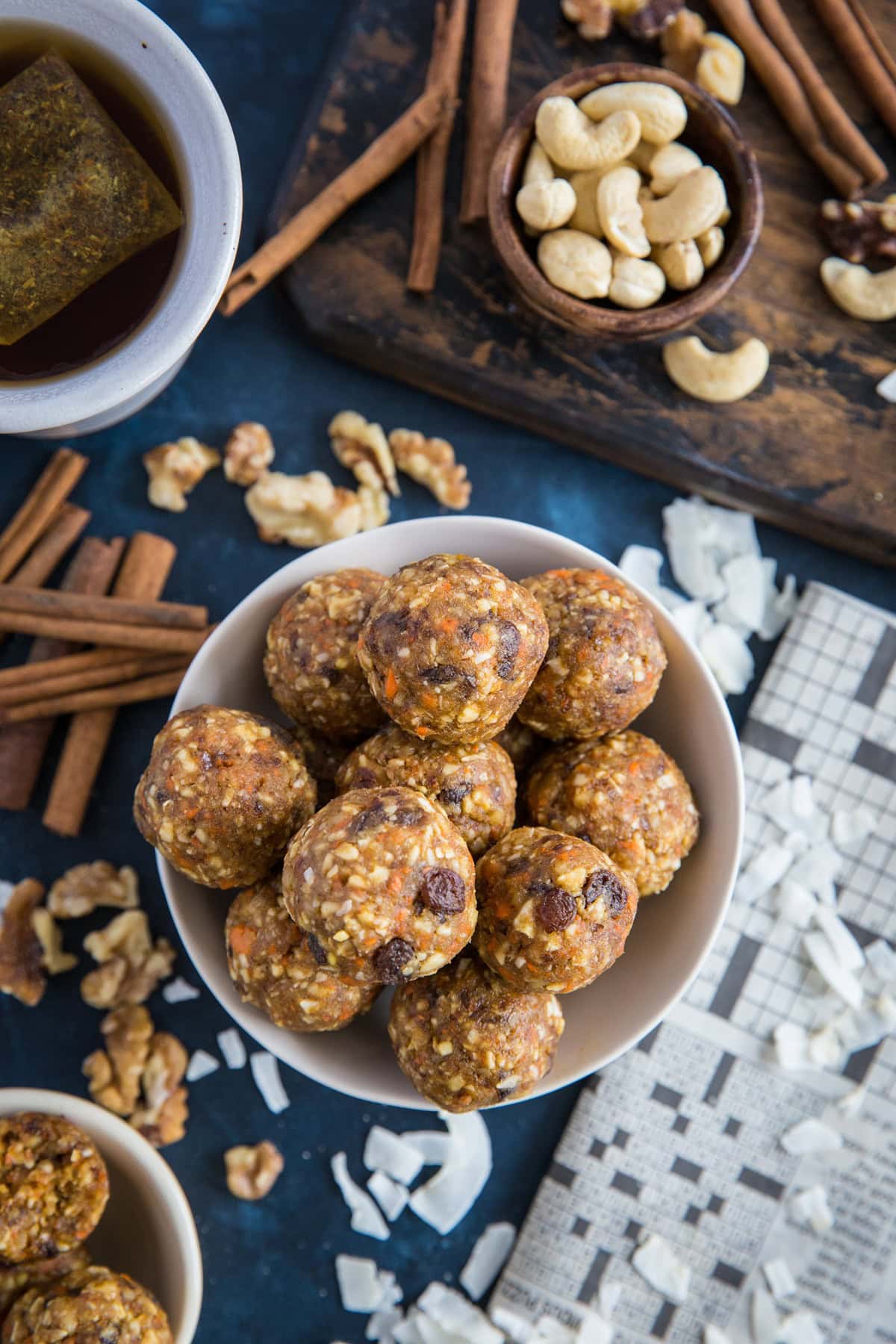 Bowl of carrot cake energy bites with nuts and cinnamon sticks around.