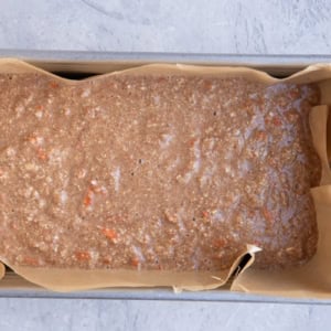 carrot ginger cake batter in a parchment-lined loaf pan.