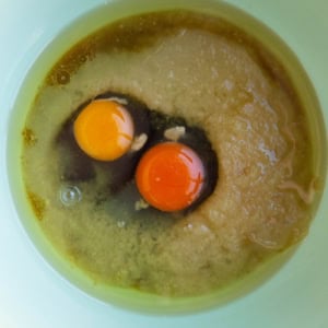 Applesauce, eggs, oil, and pure maple syrup in a mixing bowl for carrot ginger cake.