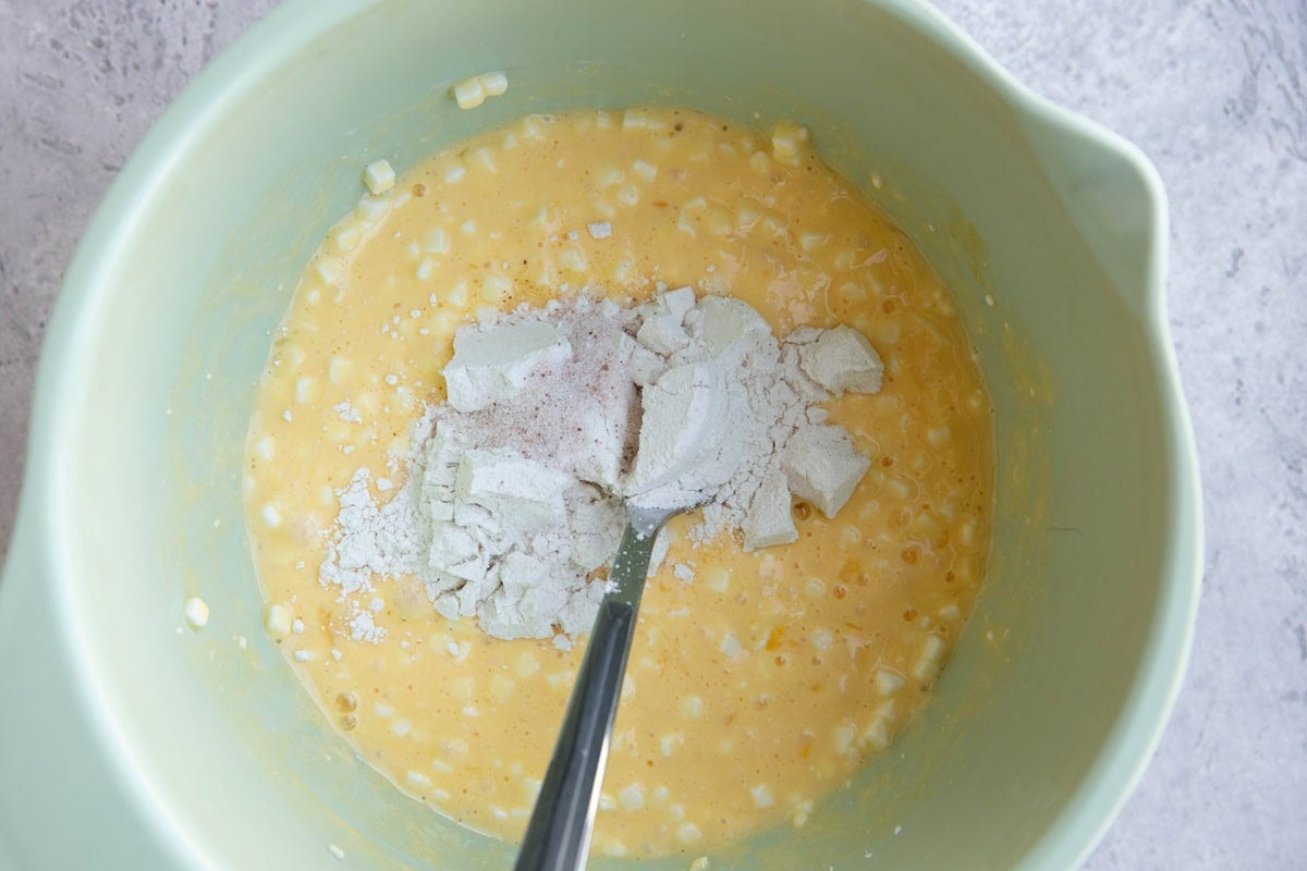 Mixing bowl full of cottage cheese, eggs, and flour sprinkled on top to be mixed in.