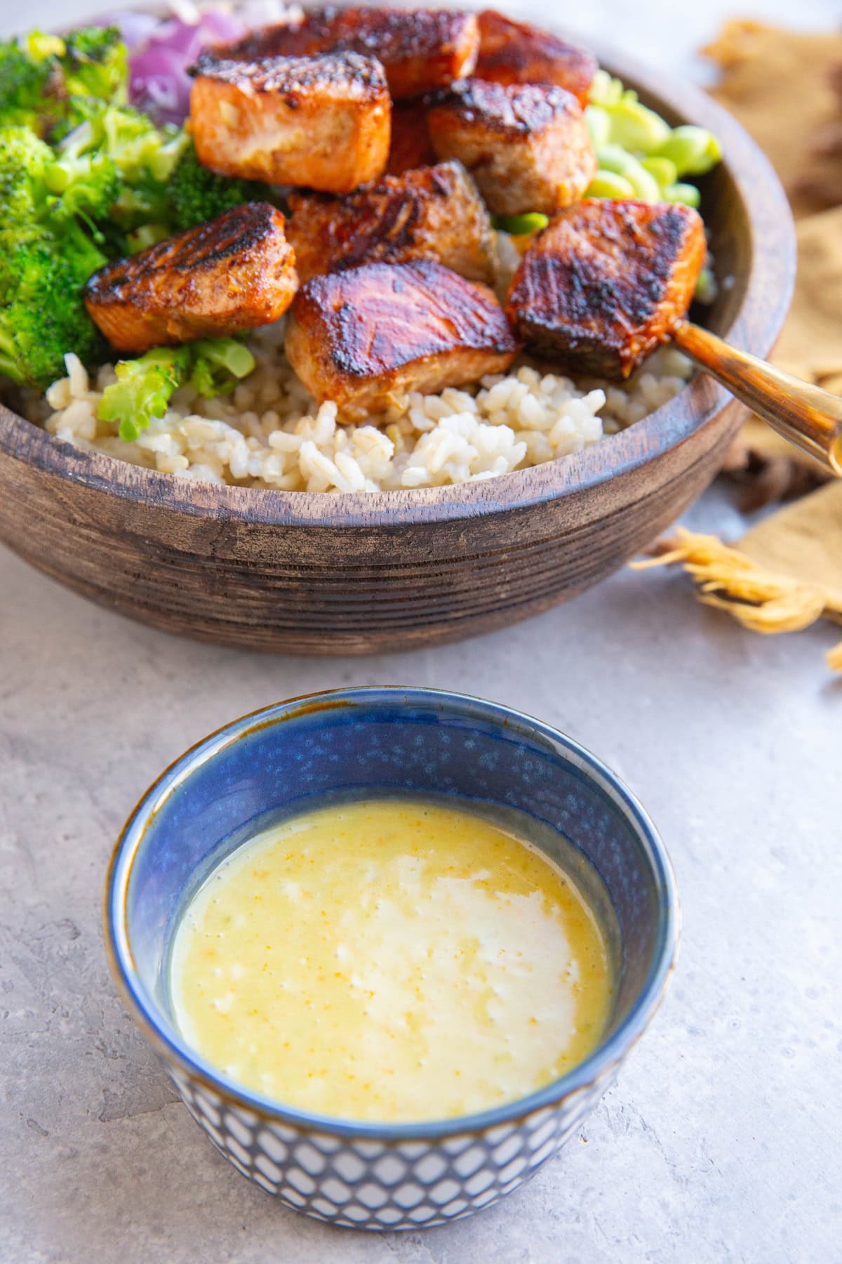 Small blue bowl of mojo sauce with a bowl of salmon bites in the background.