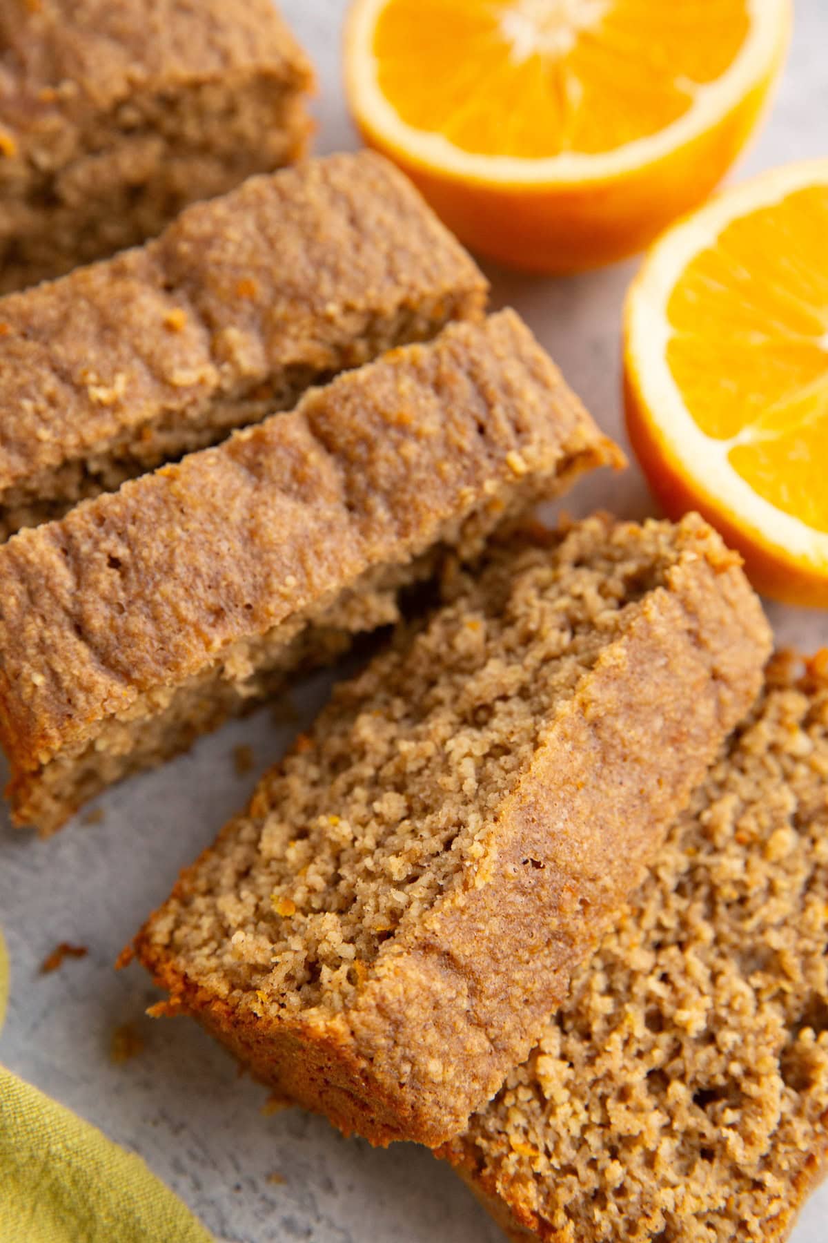 Orange loaf cut into individual slices with a fresh orange sliced in half to the side.