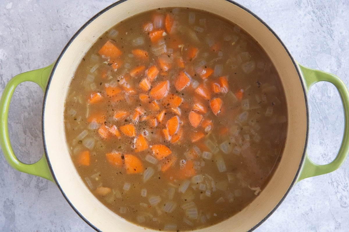 Large pot of split pea soup with carrots inside.