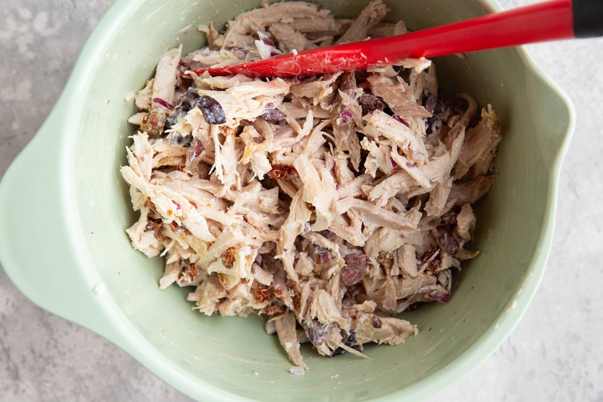 Mediterranean rotisserie chicken salad in a mixing bowl all mixed up and ready to eat.