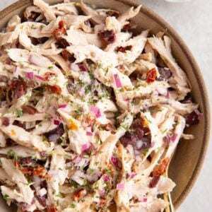 Large ceramic bowl full of Mediterranean Rotisserie Chicken Salad with a gold spoon and a gold napkin.
