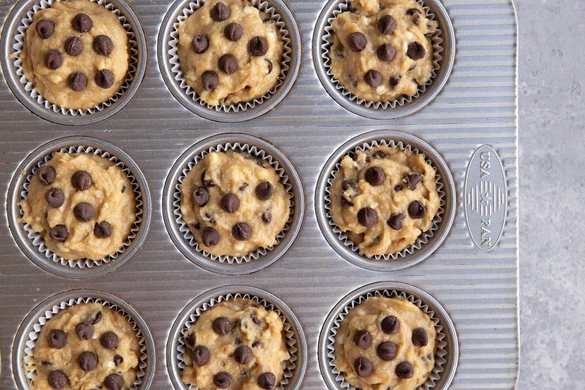 Muffin pan with raw muffin batter inside to be baked.