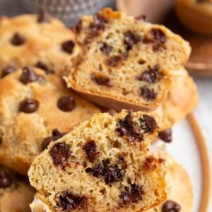 Plate of chocolate chip muffins with one sliced in half so you can see the inside.