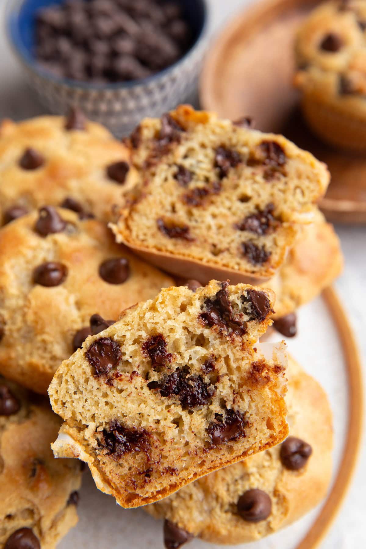 Plate of chocolate chip muffins with one sliced in half so you can see the inside.