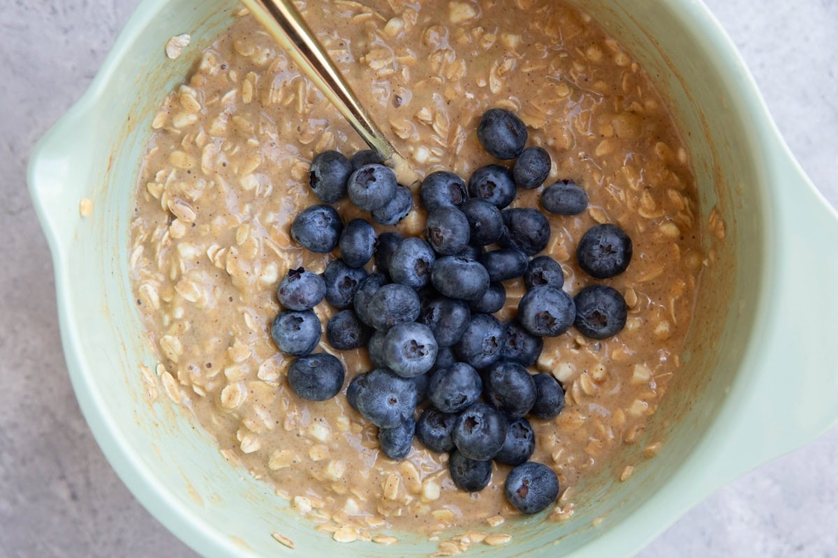 Mixing bowl with breakfast bake mixture with blueberries on top to be mixed in.