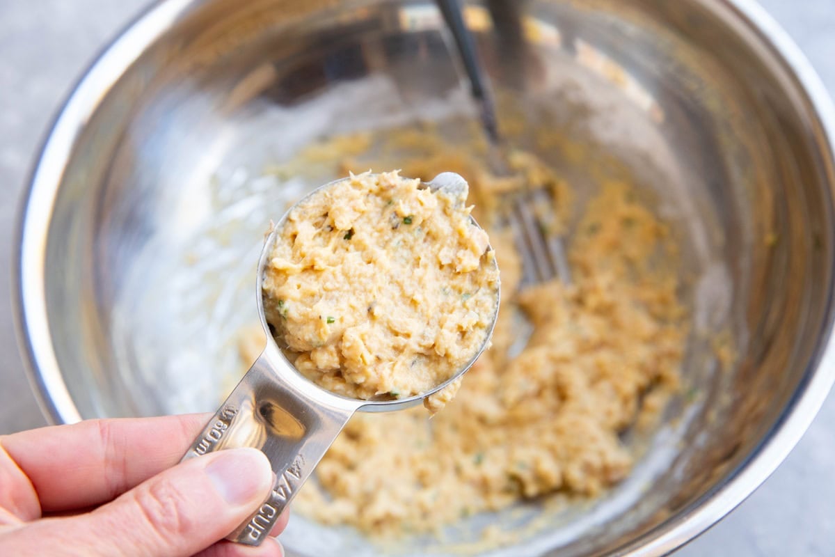 1/4 cup measuring cup measuring out salmon patty mixture, to be pan seared.