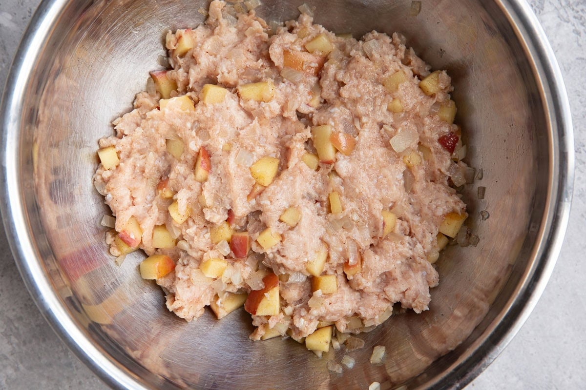 Mixing bowl full of chicken with chopped apples to make sausage