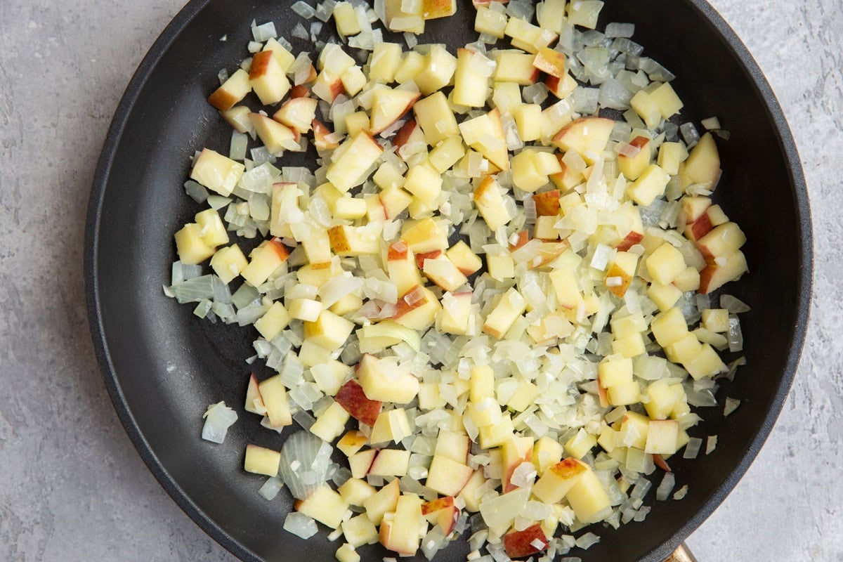Skillet with sauteed onion and chopped apple to be used in sausage.