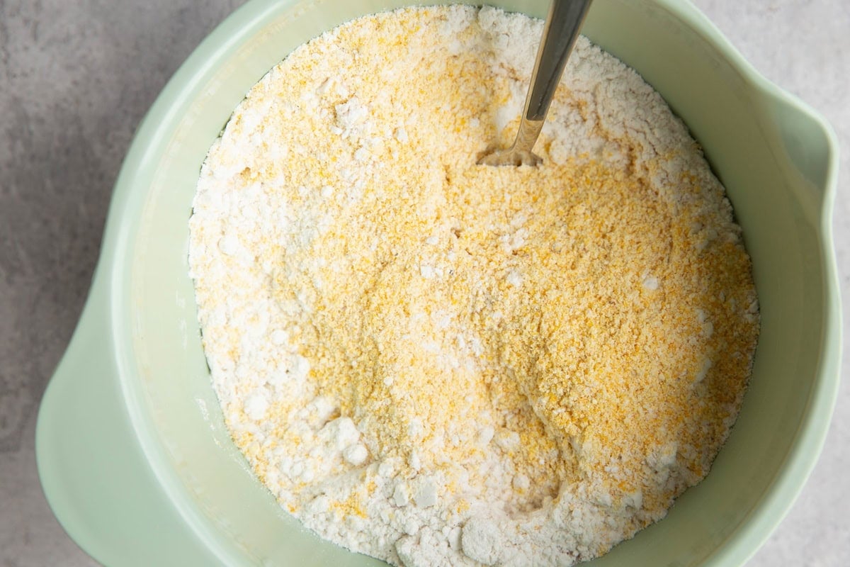 Corn meal and all-purpose flour in a mixing bowl with a fork, to be stirred together.