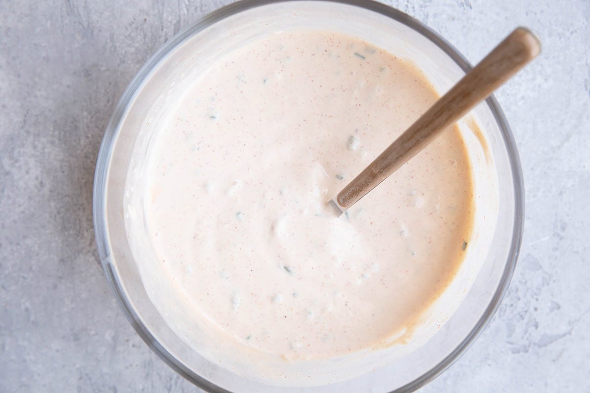 Glass bowl full of crab cake sauce that has been mixed up with a spoon. Ready to use on crab cakes or anything else.