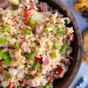 large wooden bowl full of Hawaiian rice with a bowl of chopped onions and chop sticks to the side.