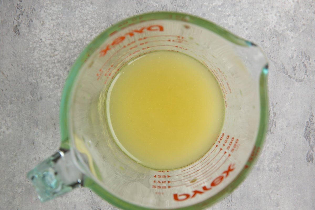 Measuring cup with olive oil and lemon juice mixed together for salad dressing.