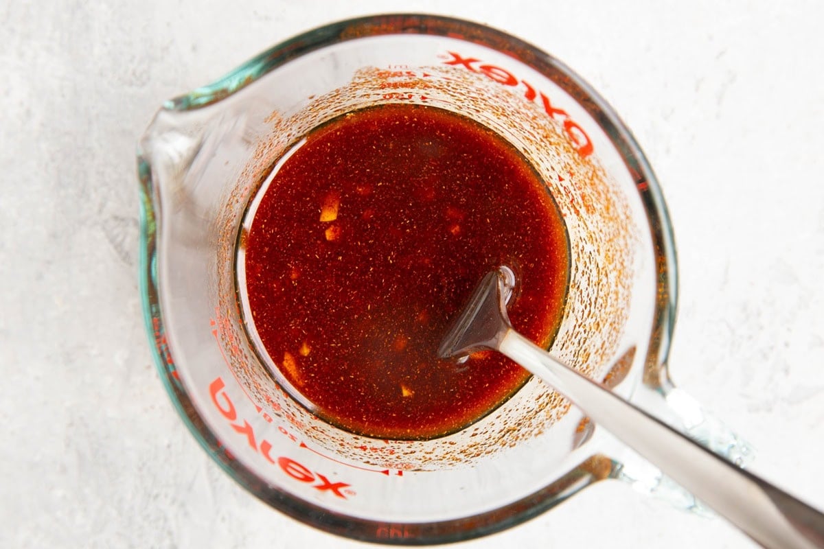 Measuring cup full of marinade ingredients to be used for chicken.
