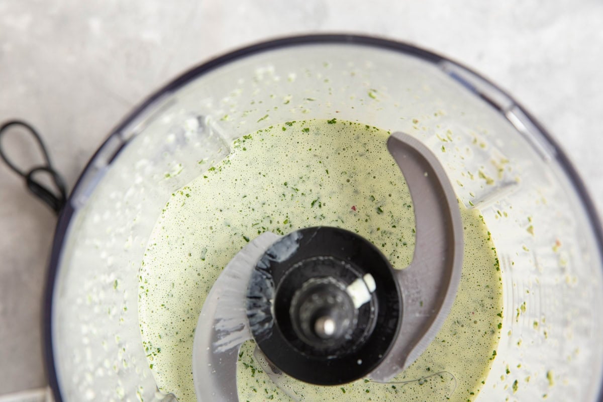 Food processor full of creamy green sauce, smooth and ready to use.