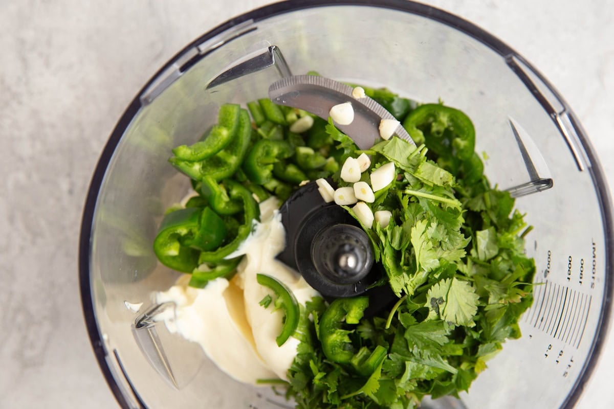Food processor full of mayonnaise, cilantro, jalapeno, and fresh garlic to make aji verde sauce.