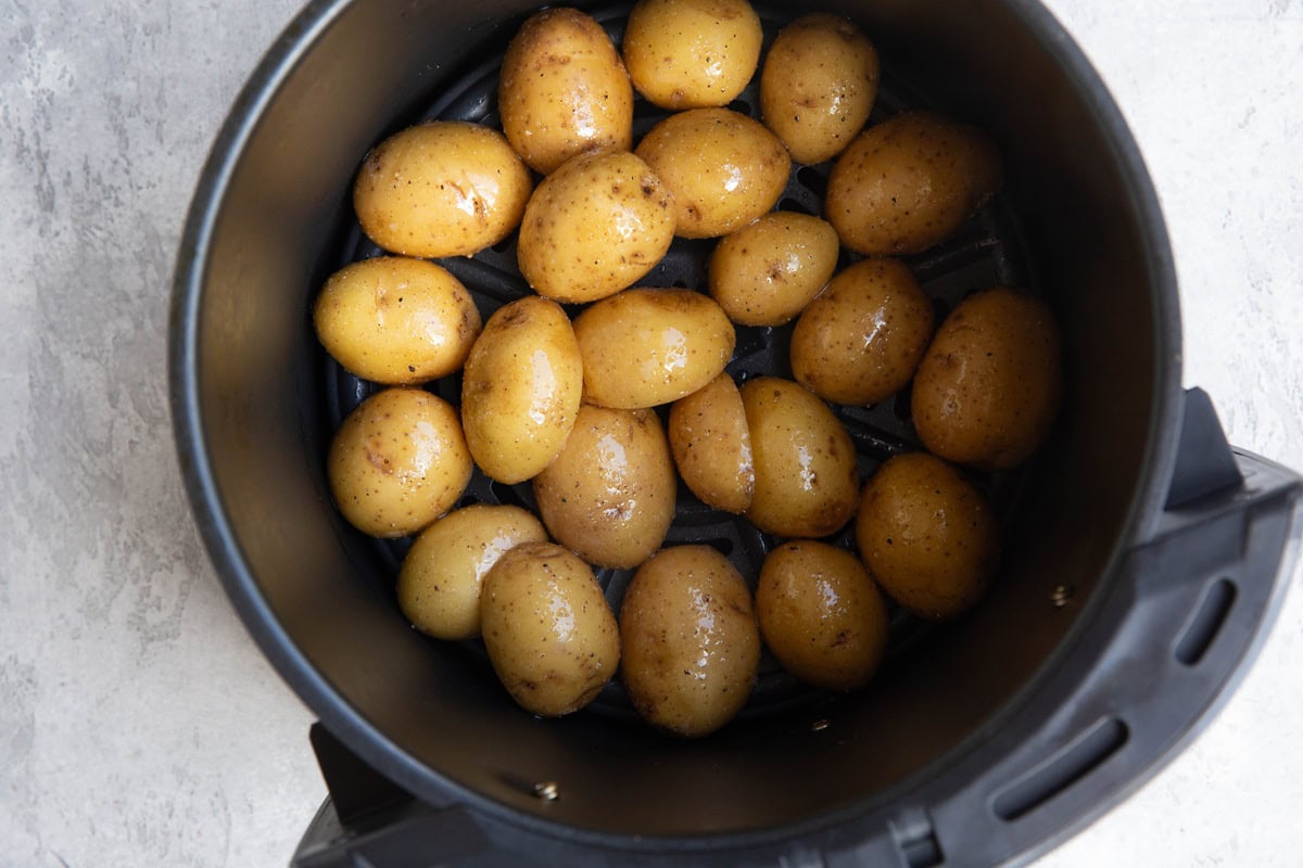 Baby potatoes in the basket of an air fryer cut-side down, waiting to be air fried