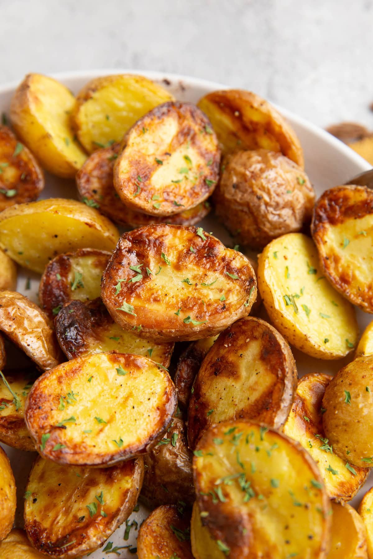 Close up on baby potatoes that have been cut in half and cooked to golden brown perfection and sprinkled with dried parsley.