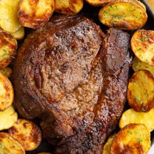 Chuck roast on a black plate with golden cooked potatoes surrounding it, ready to serve.