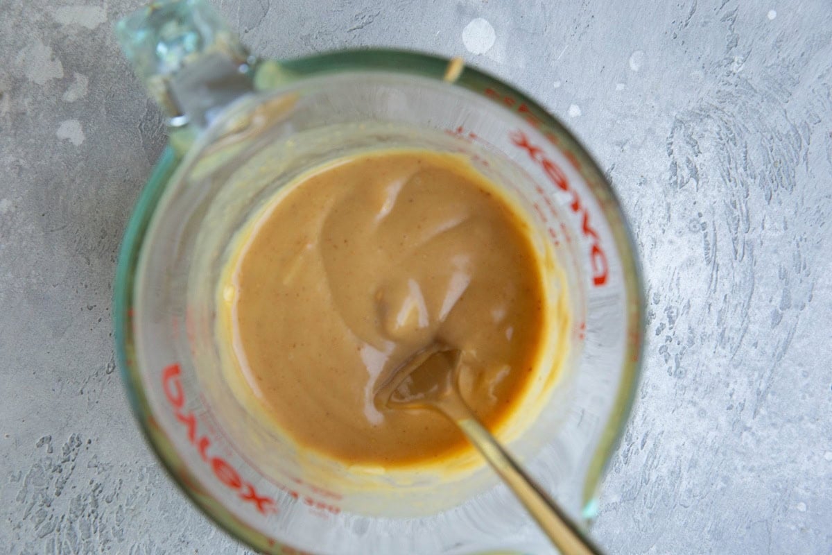 Measuring cup full of peanut dressing, all mixed up and ready to use.
