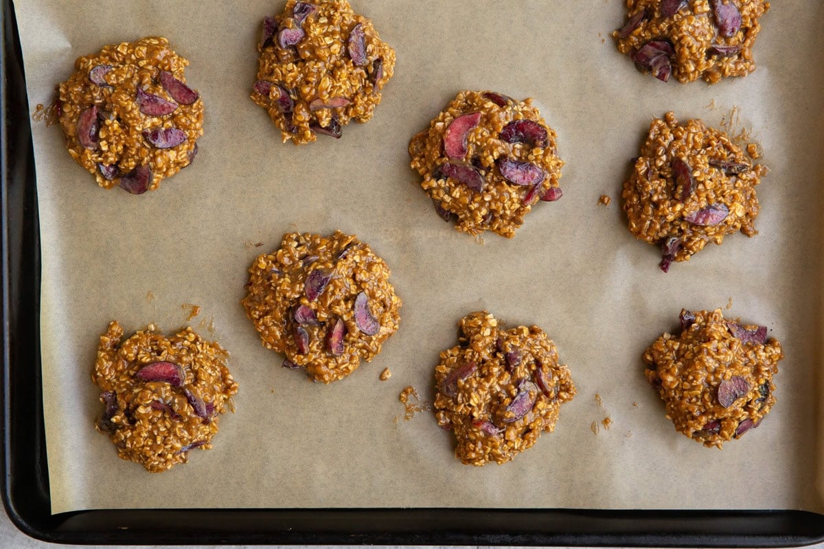 Mounds of cherry cookie dough on a parchment-lined baking sheet, ready to go into the oven.