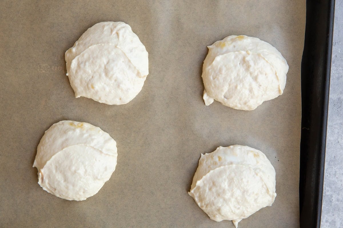 Baking sheet lined with parchment paper with globs of yogurt banana mixture, to be frozen into frozen yogurt treats.