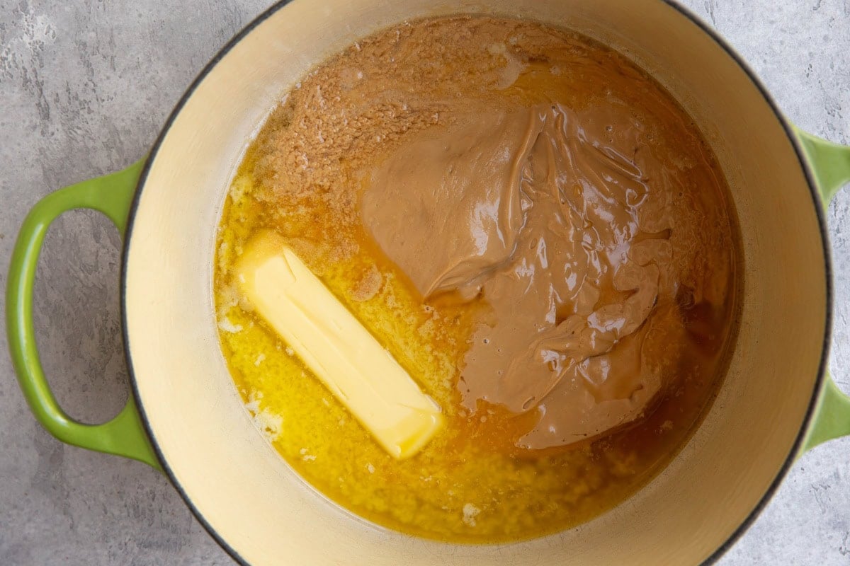 A large green pot containing melted butter, creamy peanut butter, and honey melting to be mixed together.
