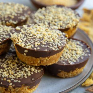 Plate of crunchy peanut butter cups with puffed quinoa and a bowl of crispy quinoa in the background, ready to serve.