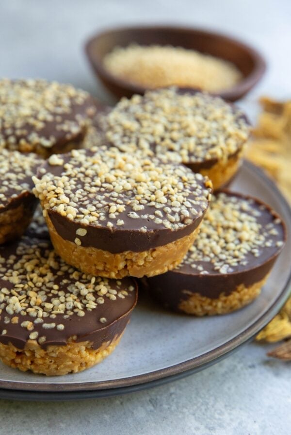 Plate of crunchy peanut butter cups with puffed quinoa and a bowl of crispy quinoa in the background, ready to serve.