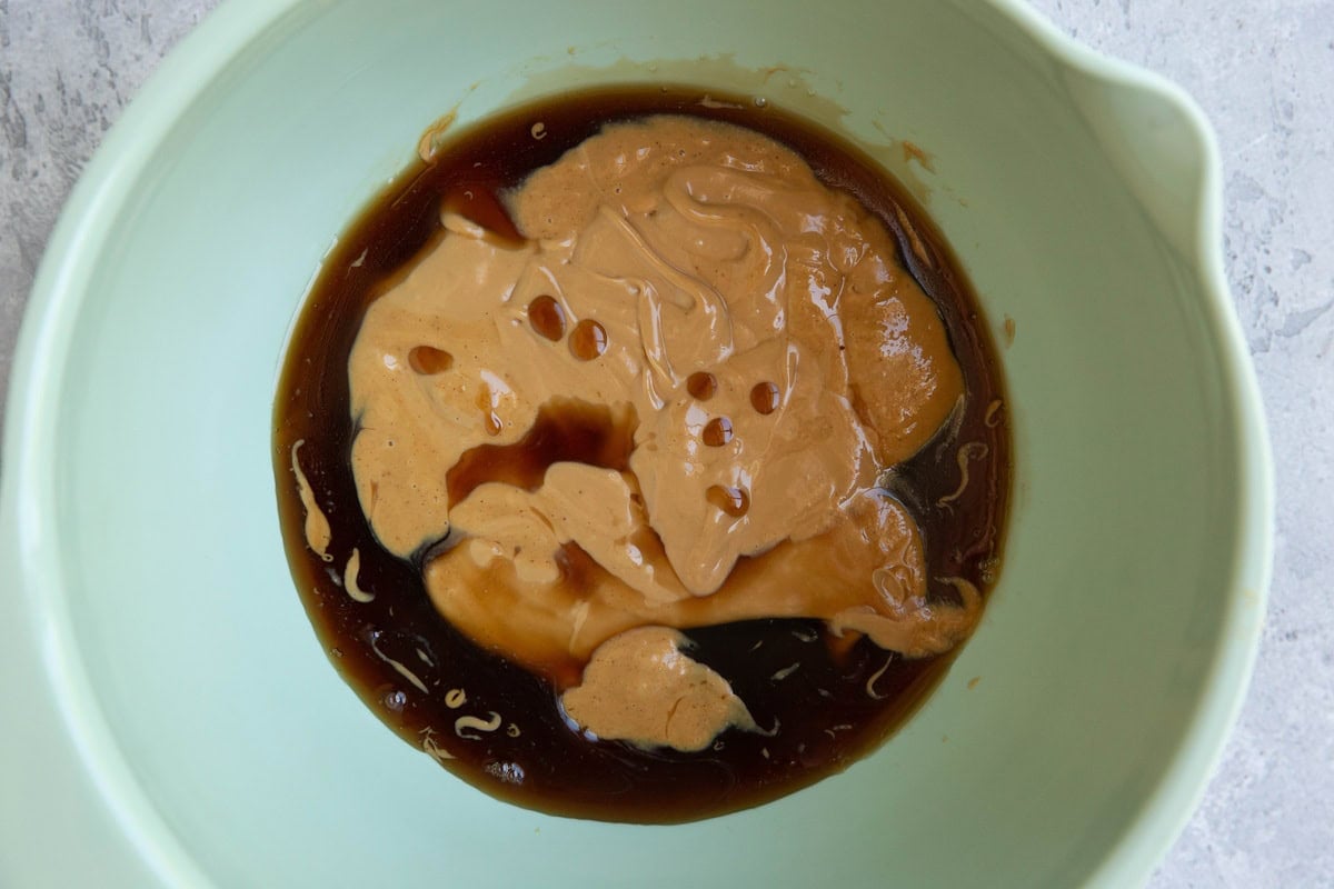 Mixing bowl with peanut butter and pure maple syrup inside, ready to mix together.