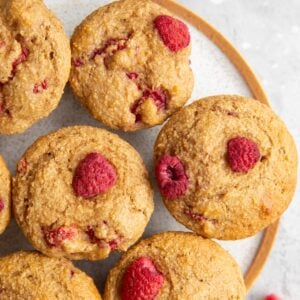 Plate with raspberry muffins and fresh raspberries to the side. Ready to serve.