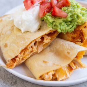 Three slices of chicken and cheese quesadilla with sour cream and guacamole on top.