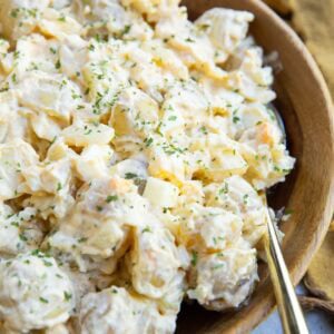 Cottage cheese potato salad in a large wooden bowl with a gold spoon and a gold napkin to the side.