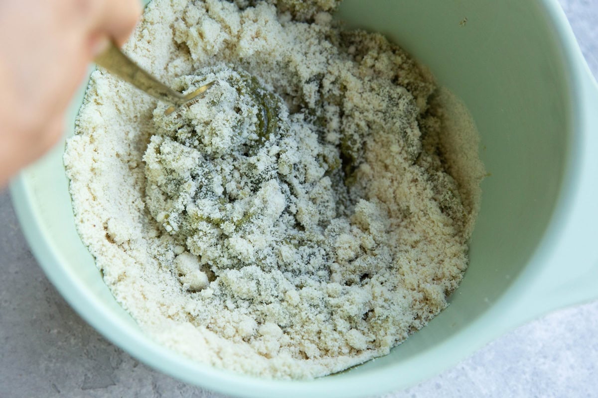Mixing bowl with pistachio butter and almond flour being mixed together to make cookie dough.