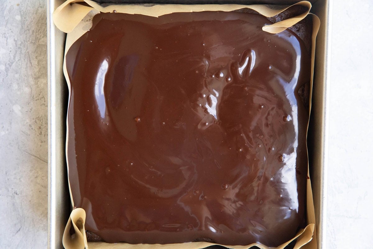 Cake pan with chocolate cake covered in chocolate ganache.