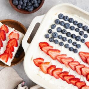 Large baking dish filled with fourth of July cake with a slice on a wooden