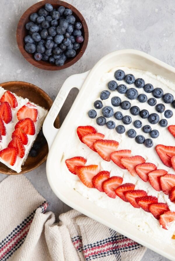 Large baking dish filled with fourth of July cake with a slice on a wooden