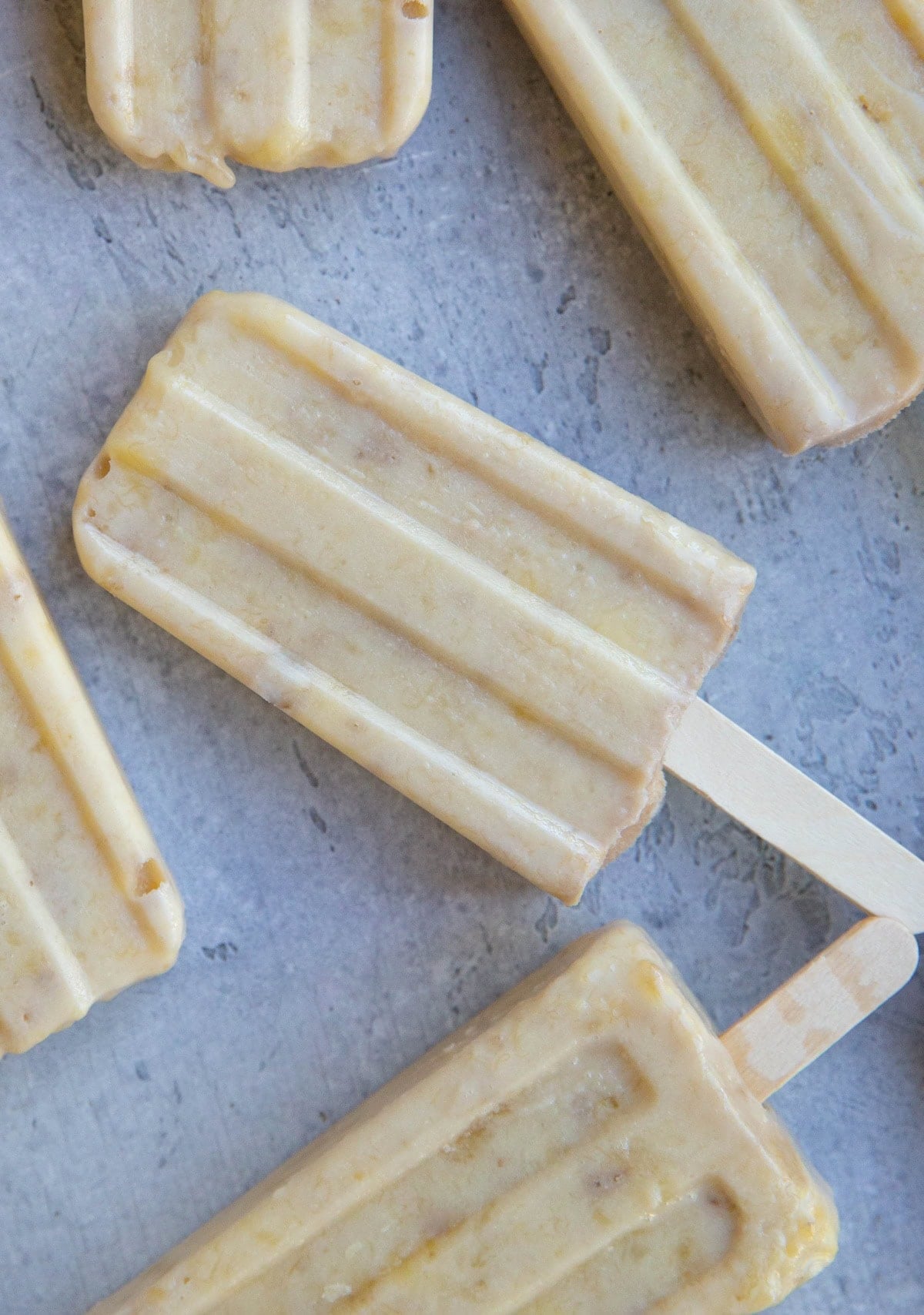 Five banana popsicles on a blue backdrop.