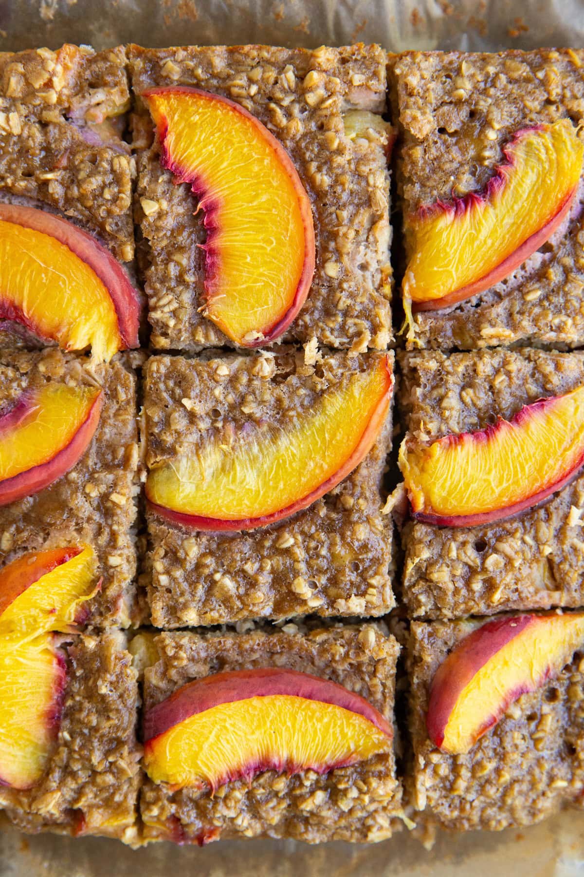 Sliced peach baked oatmeal on a sheet of parchment paper, ready to serve.