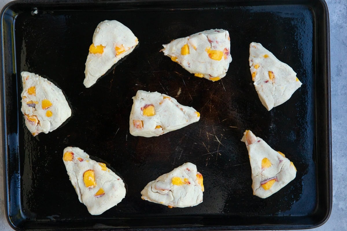 Baking sheet with unbaked scone dough in the form of eight triangles, ready to go into the oven.