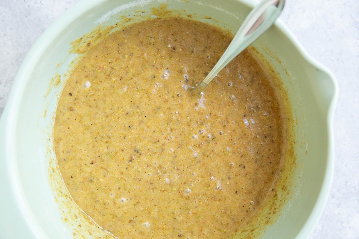 Mixing bowl full of pistachio cake batter with a fork.